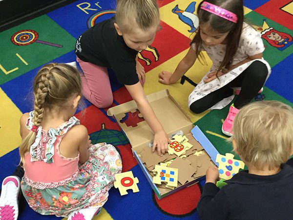 Children at JumpStart working together on a puzzle on a colourful classroom rug